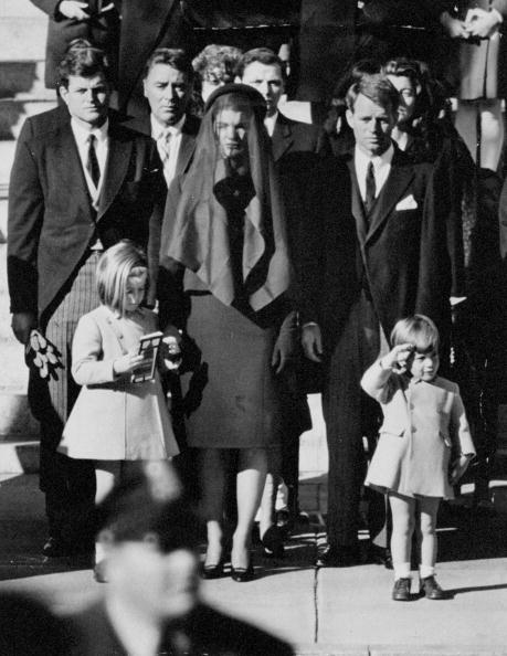 Relinquishing his mother's hand, John F. Kennedy Jr. salutes