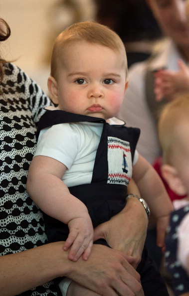 Catherine (L-out of frame), the Duchess of Cambridge, holds Prince George during a Plunket nurse and parents group visit at Government House in Wellington on April 9, 2014. Plunket is a national not-for-profit organisation that provides care for children and families in New Zealand. Britain's Prince William, Kate and their son Prince George are on a three-week tour of New Zealand and Australia.    AFP PHOTO / POOL / MARTY MELVILLE (Photo credit should read Marty Melville/AFP/Getty Images)