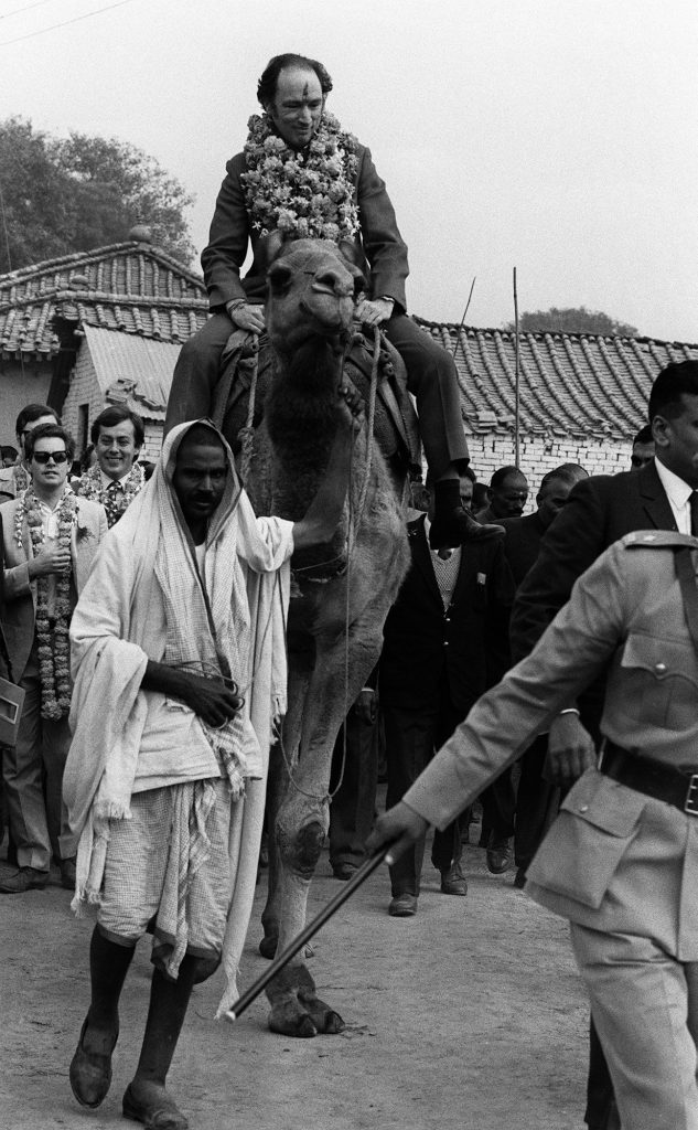 Prime Minister Pierre Trudeau, with a garland around his neck and a Hindu greeting symbol in paste on his forhead, rides a camel Jan 12, 1971 in the village of Benares, India, where he dedicated a well. (CP PHOTO/ Peter Bregg)