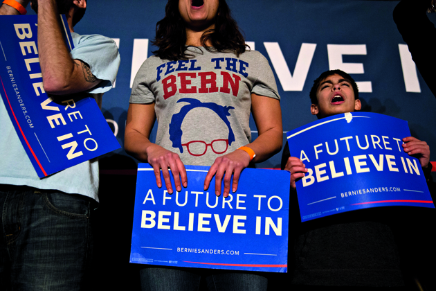 Attendees hold campaign signs and cheer during a campaign rally for Senator Bernie Sanders, an independent from Vermont and 2016 Democratic presidential candidate, at Danceland Ballroom in Davenport, Iowa, U.S., on Friday, Jan. 29, 2016. Sanders is counting on young voters turning out to win next Mondays Iowa caucuses. But by putting an emphasis on his plans for Social Security, the Vermont Senator isnt ceding older Democrats to Hillary Clinton. Photographer: Andrew Harrer/Bloomberg via Getty Images