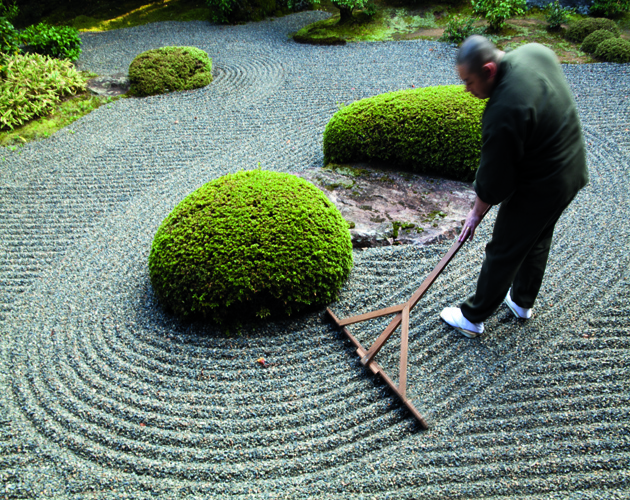 KYOTO, JAPAN - 2010/11/20: Rev Takafumi Kawakami is the vice-abbot at Shunkoin Temple and teaches classes about Zen culture and meditation and serves as a bridge between the Eastern and Western cultures. Here Rev Takafumi is raking the temple's Zen Garden. The Garden of Bolders, or Sazareishi-no-niwa, is the main garden of Shunkoin. The theme of the garden is the Great Shrine of Ise in Mie Prefecture. The Great Shrine of Ise is the head shrine of all Shinto shrines in Japan. This garden houses a shrine to Toyouke-no-omikami, a goddess of agriculture.. (Photo by John S. Lander/LightRocket via Getty Images)