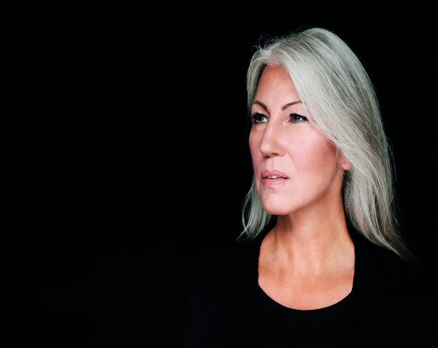 Portrait of mature woman with grey hair in front of black background
