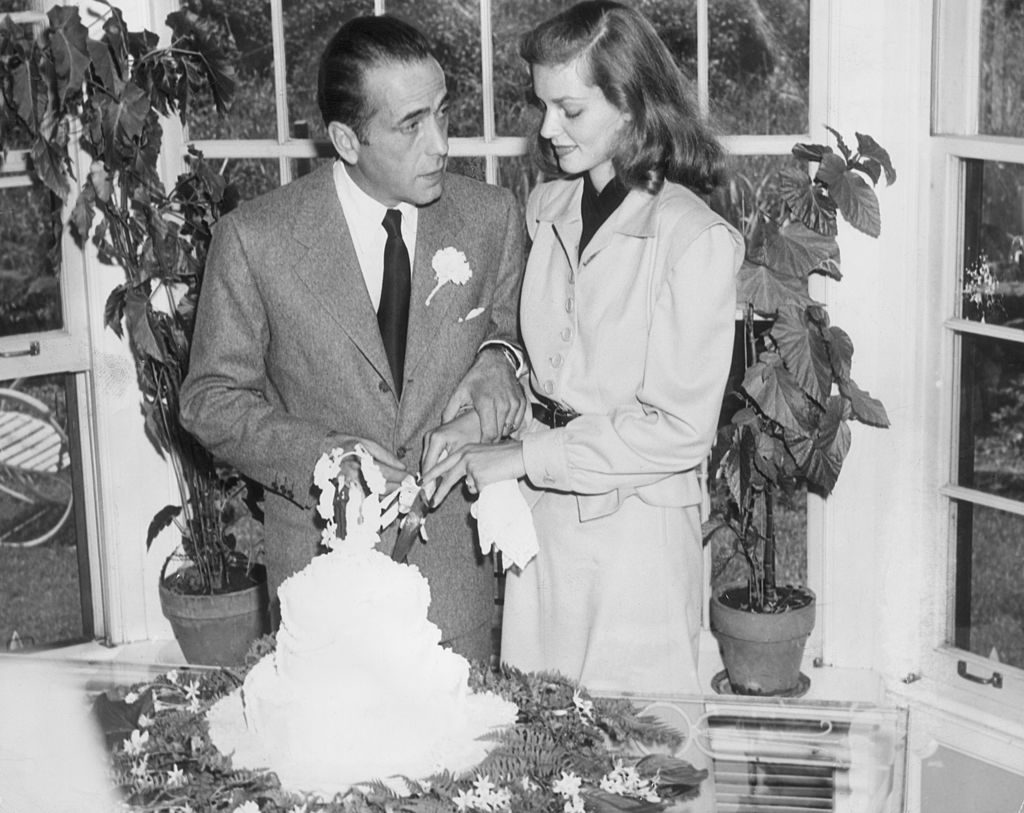 21st May 1945: Married American actors Lauren Bacall and Humphrey Bogart (1899 - 1957) cut the cake at their wedding. (Photo by Hulton Archive/Getty Images)