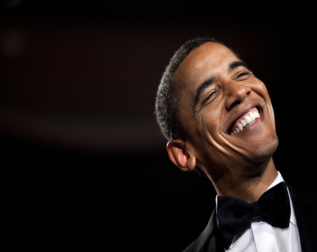 Obama smiling from ear to ear on a black background. 