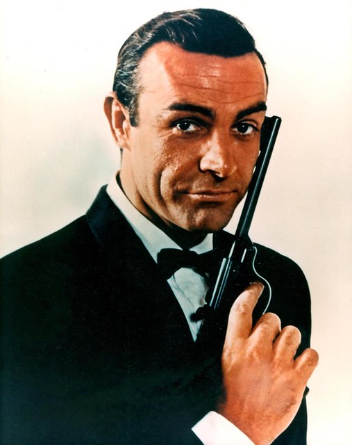 Sean Connery as James Bond holds up a pistol. 