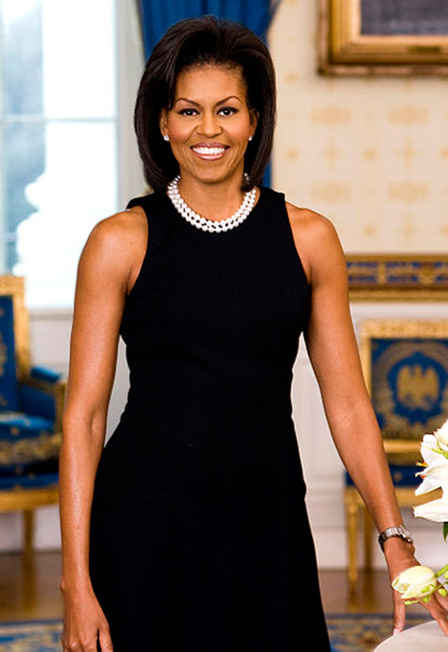 Michelle Obama wearing a sleeveless black dress and white pearls. 