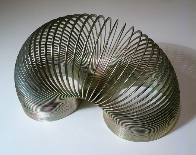A steel slinky standing on both ends. 