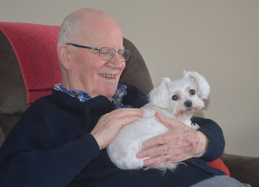 Oliver, a senior sits with his small white dog named Saffi