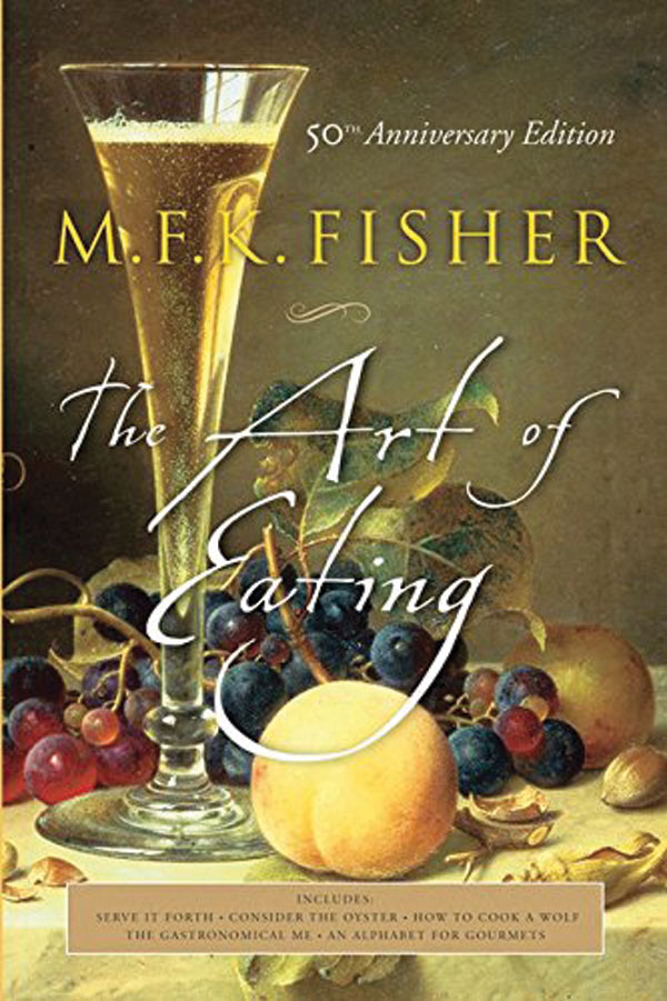 The book cover for The Art of Eating. A photo of a bunch of grapes and a peach beside a glass of wine is overlaid with the title of the book written in cursive. 