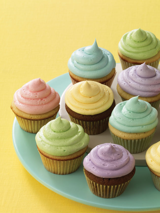 Multicoloured cupcakes sitting on a green plate. 