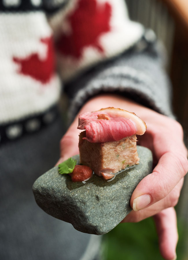 Seared duck breast on duck pâté sitting on top of a stone. 