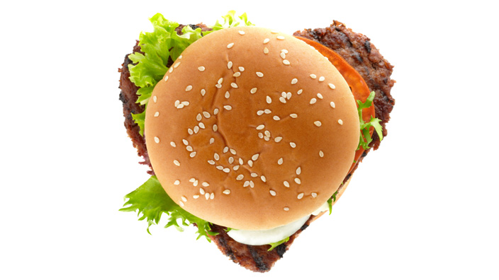 A burger with an oversized patty creating an outline of a heart shape. 