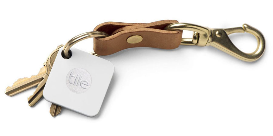 A set of keys on a leather key chain with a bluetooth tracker attached to the key ring.