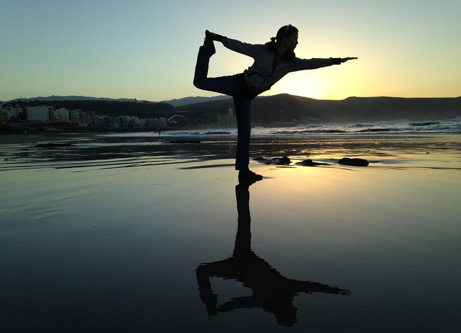 A person doing yoga with the sun setting in the background. 