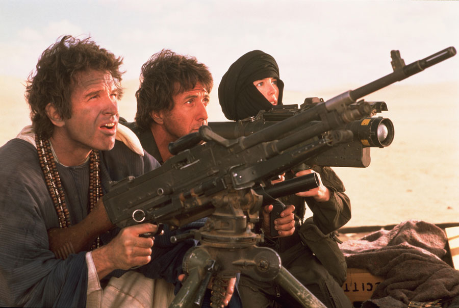 A woman with a scarf wrapped around her head and face and two men sitting behind a large machine gun.
