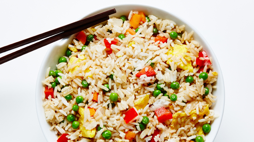 Vegetable fried rice recipe with a pair of black chopsticks sticking out. 