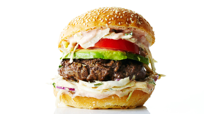 A chipotle burger with coleslaw, tomato and avocado.