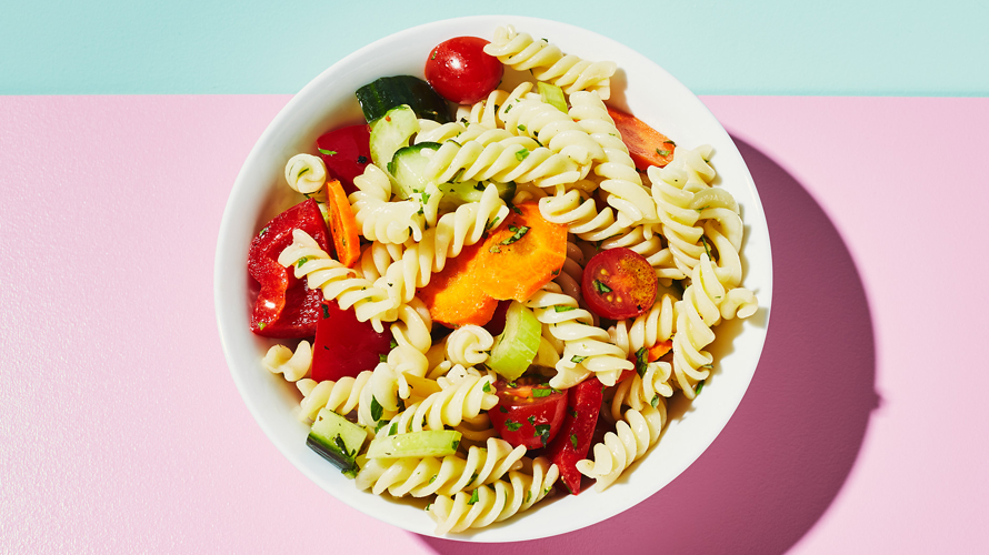 A bowl of pasta salad with peppers and baby tomatoes. 