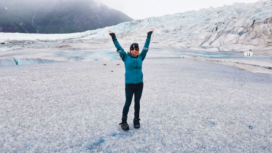 Vivian Vassos with her armed stretched over her head as she stands on the solid ice of Mendenhall Glacier. 