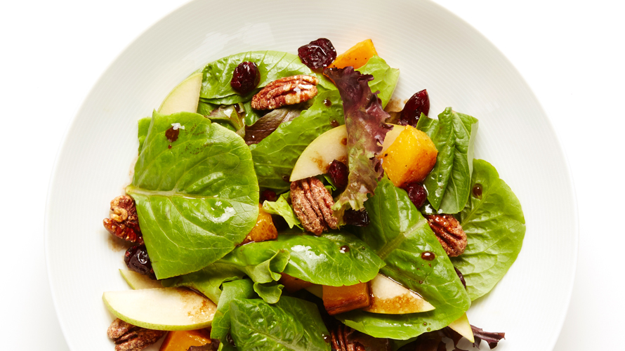 A colourful Squash, pecan and pear salad in a white bowl. 