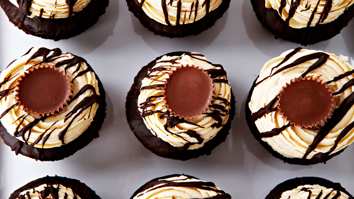 Cupcakes with mini peanut butter cups sitting on top of white icing. 