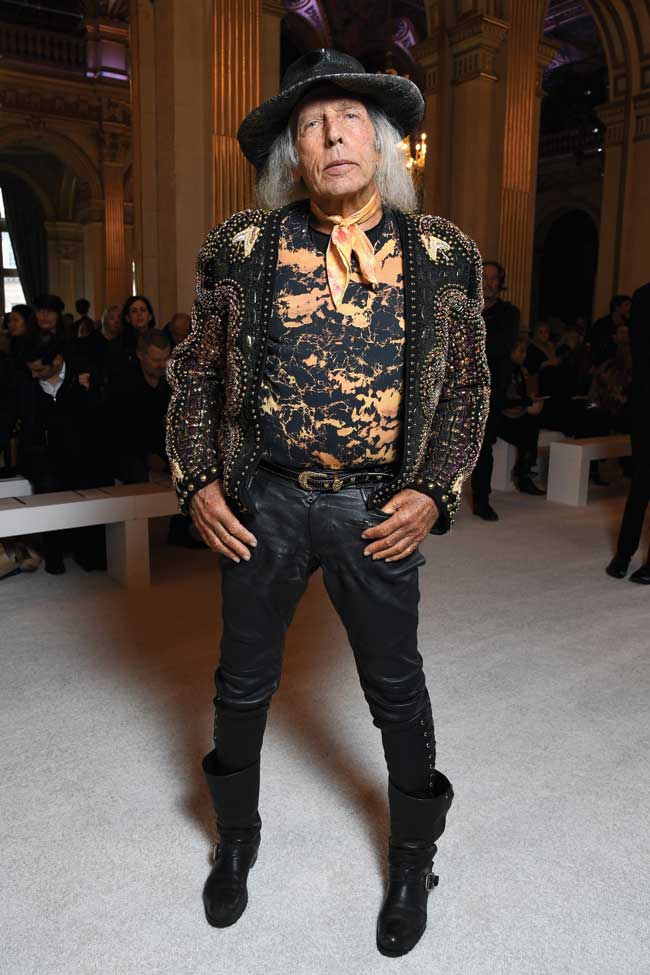 James Goldstein wearing a gold studded jacket, a cowboy style hat and boots. 