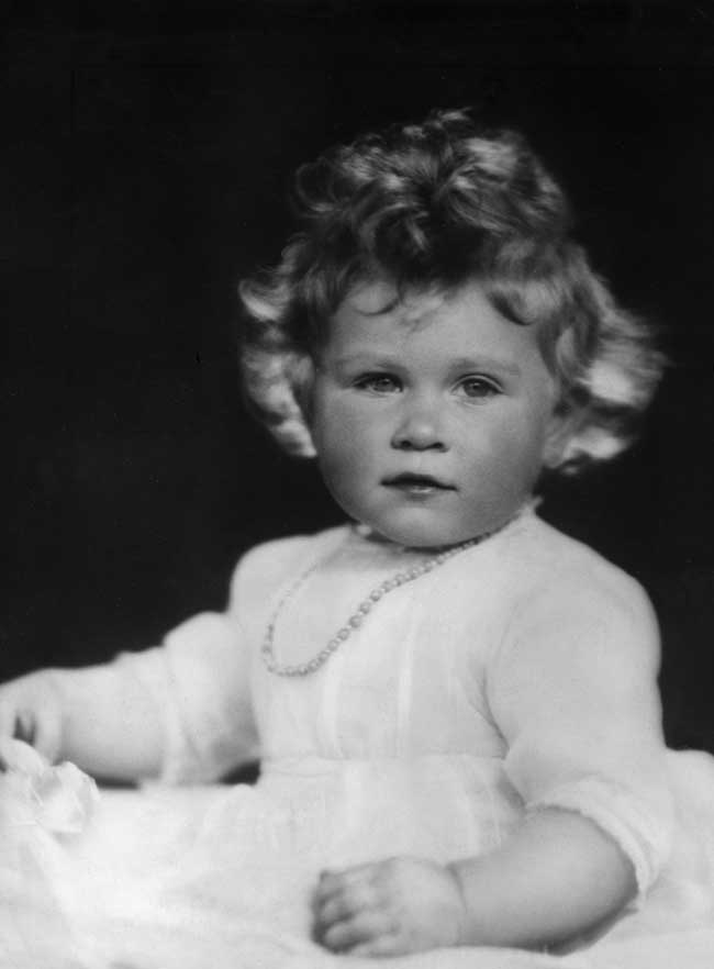 Queen Elizabeth as an infant wearing a white dress.