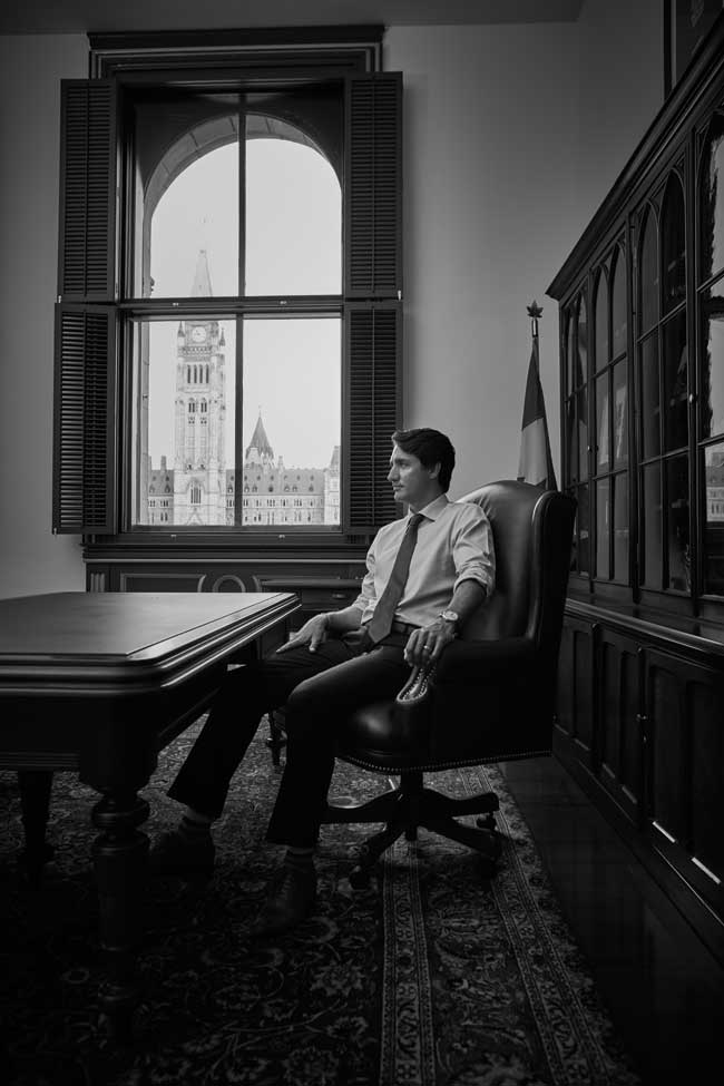 A black and white photo of Justin Trudeau sitting in his office in Ottawa. 