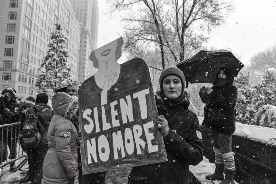 A woman holds up a sign that reads silent no more during a woman's rally. 