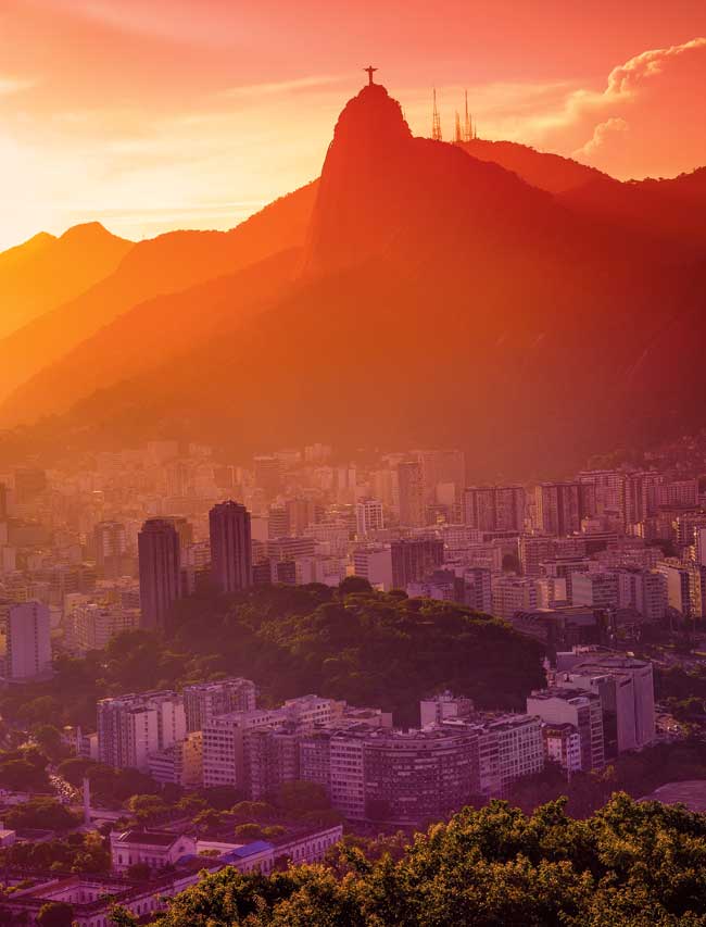 A photo of Rio at sunset with the remaining sun falling over the city and mountains in the background.