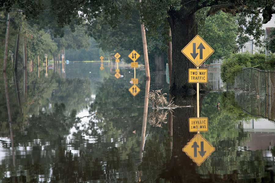 A flooded road with two way traffic signs sticking out from the lake of water. 