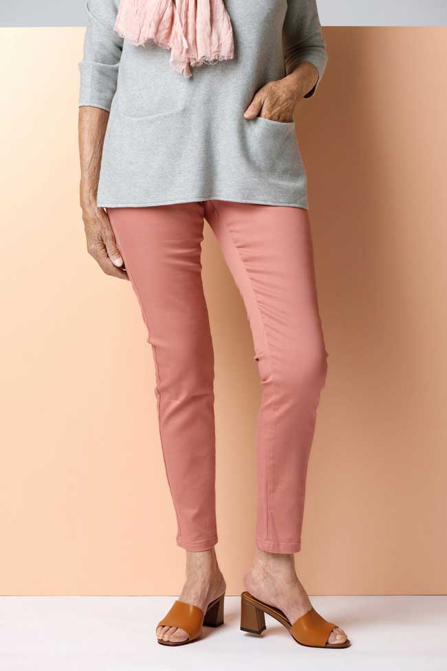 A woman wearing a grey top with a pink scarf and pink pants. The outfit completed with a brown shoe. 