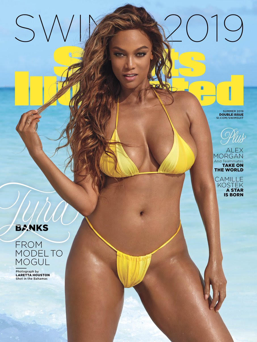 Tyra Banks holding a few strands of hair between her fingers wearing a yellow bikini.