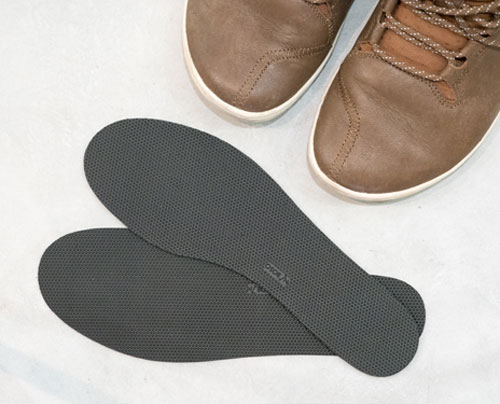 A pair of shoe insoles pictured with a pair of casual shoes