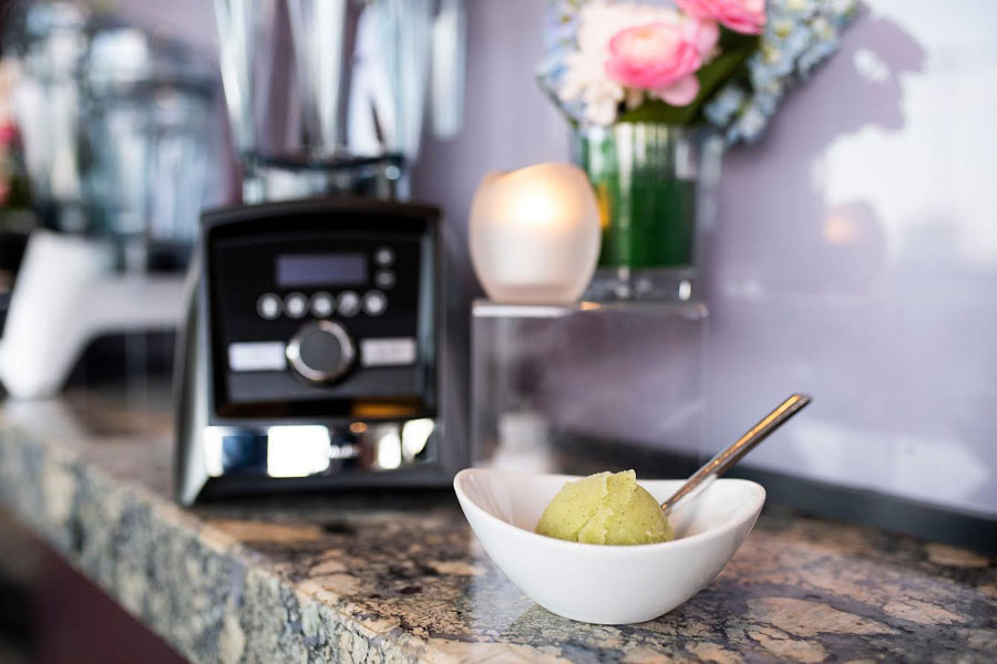 Melon Mint Sorbet in a white bowl sitting in front of a blender. 