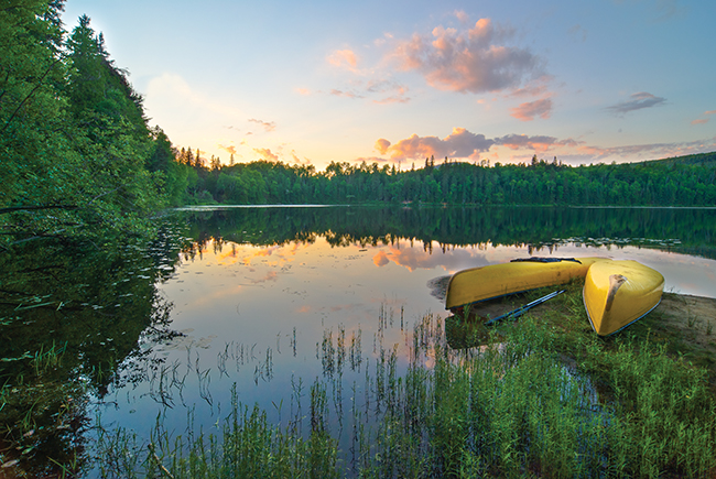 A photo of a pair of canoes by the lake during sunset at Algonquin Park.
