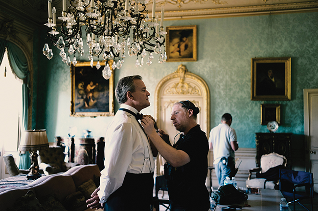 A photo of Hugh Bonneville as Lord Grantham getting into costume on the set of Downton Abbey.