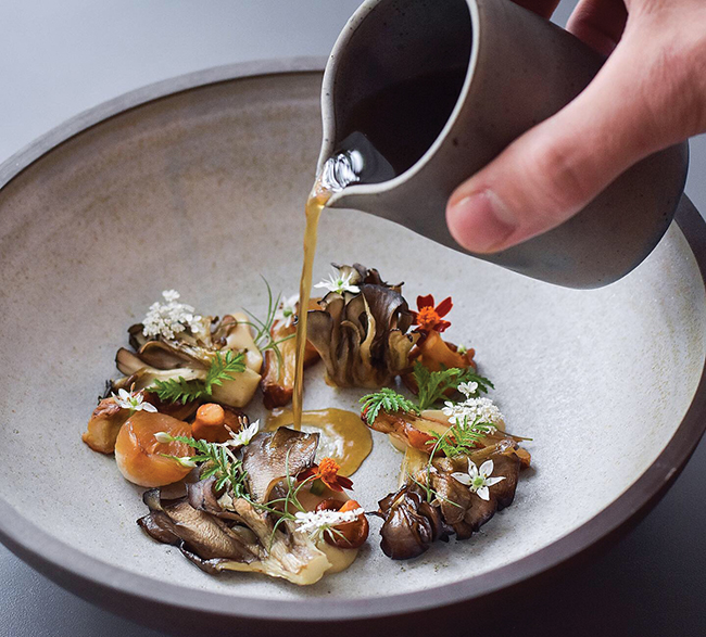 A picture of Grilled and roasted wild mushrooms, chared onions and foraged herbs with mushroom dashi broth from Est.
