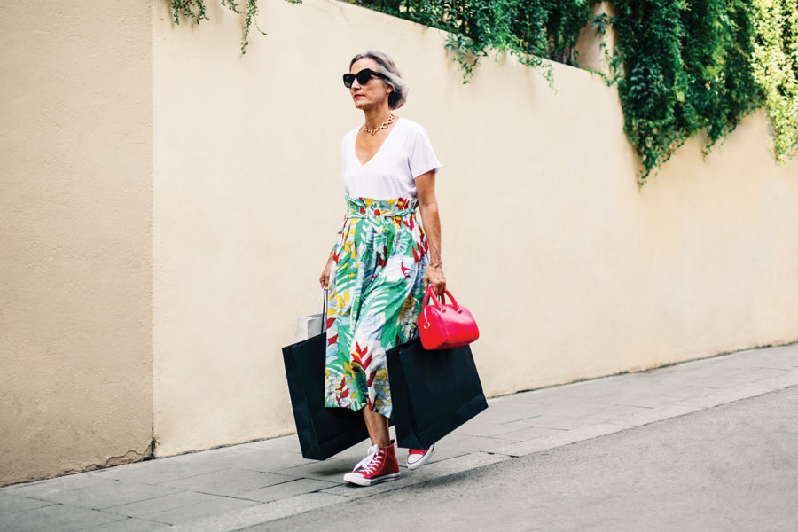 Woman in bright coloured floral long skirt wearing red chuck sneakers. 