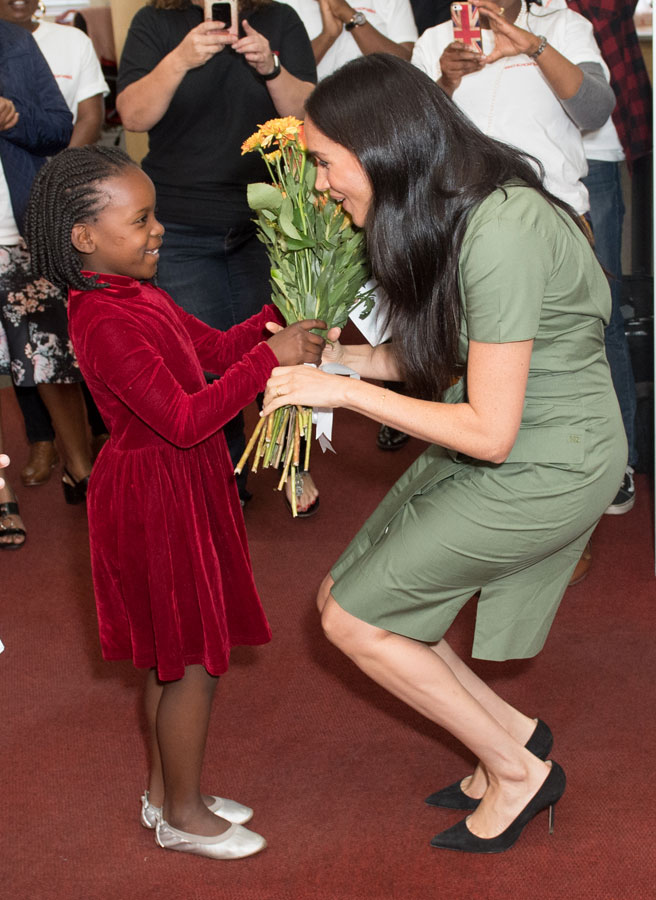 Meghan Markle accepts flower from a child a an Action Aid event during her royal tour of South Africa. 