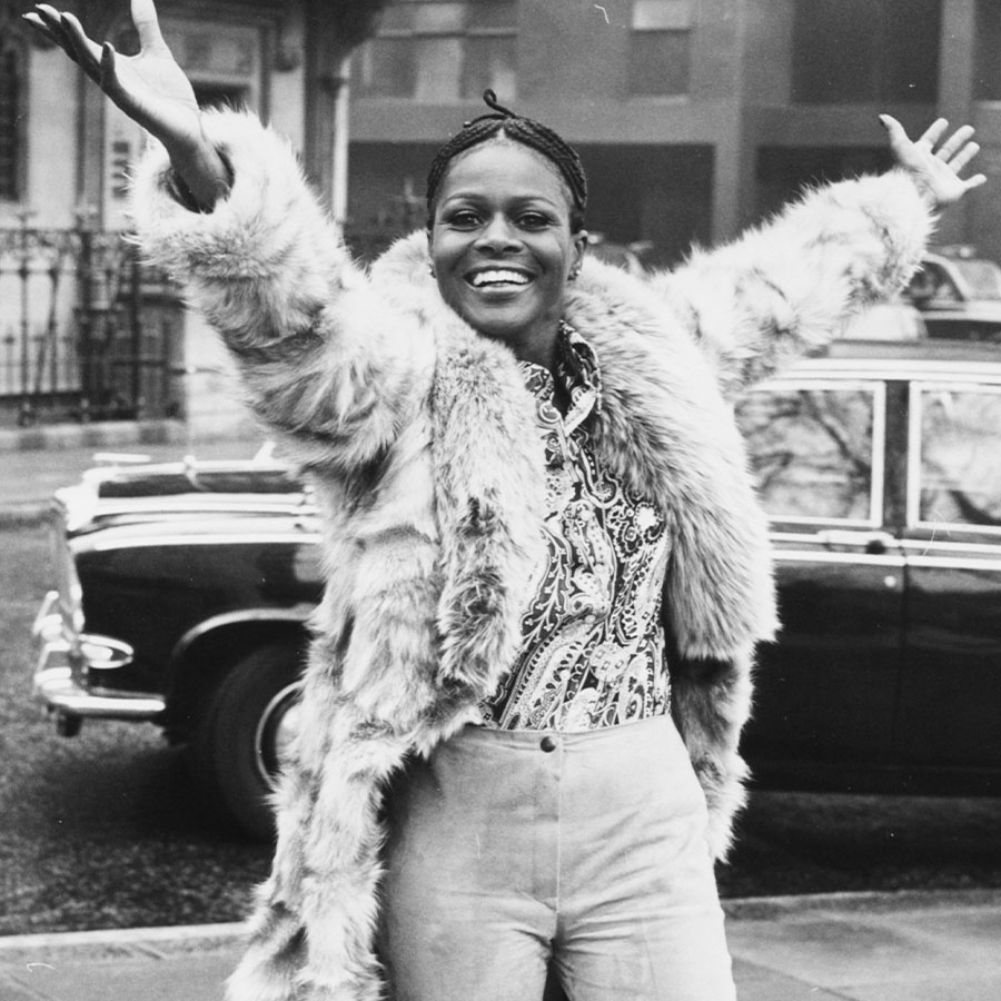 Portrait of Academy Award winning American actress Cicely Tyson smiling and raising her arms in the air during a visit to London.